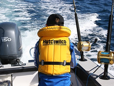 Child on boat in yellow Hutchwilco lifejacket facing away from camera